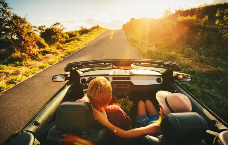 a couple on a road trip in their new automobile