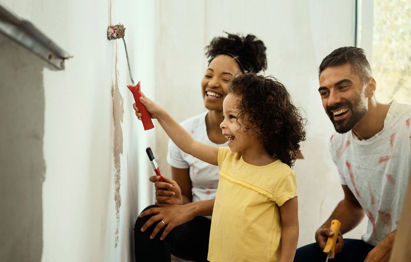 a child painting a wall with their mom and dad