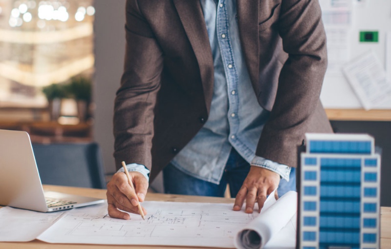 a businessman writing on building drafts forms