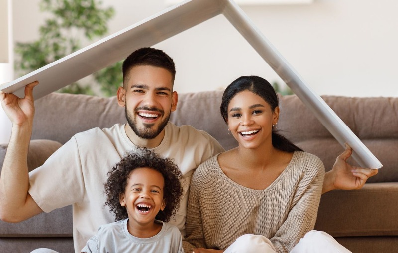 a family of three smiling in their living room