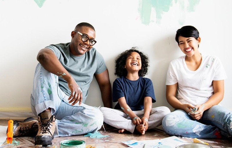 a family of three painting a wall in their new home